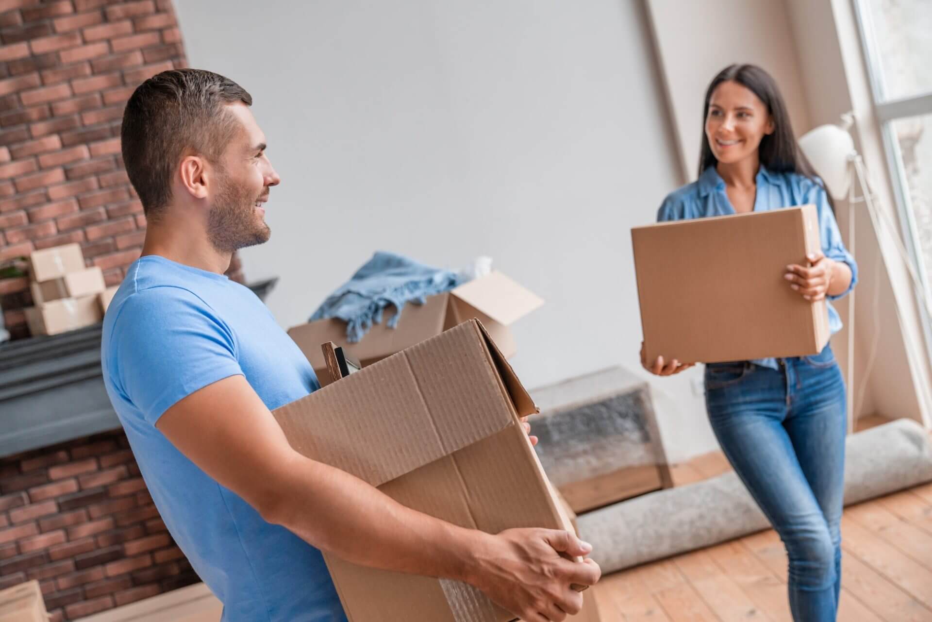 Happy couple carrying boxes in moving house